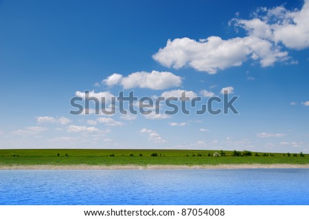 water and green field under deep blue cloudy sky