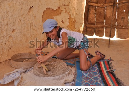 The girl grinding flour in the mill. Tourism in ezgotycznych countries. Round trip. Berber culture.