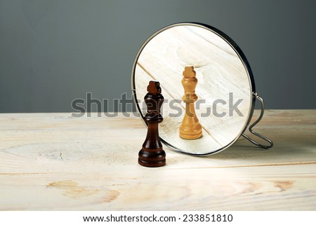 Black or white king chessmen in front of the mirror, concept about racism.