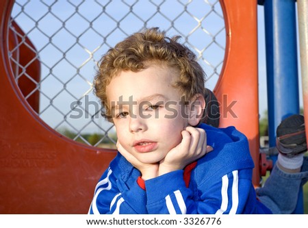 Young boy laying on playground equipment outdoors/outside