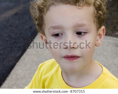 Young boy outside giving sideways curious look