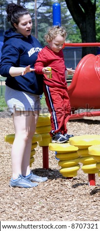 Older sister helping younger brother on playground equipment