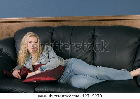 Beautiful blond model laying on black leather couch