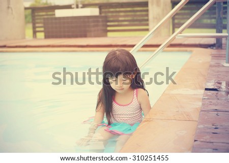 adorable asian girl sit in swimming pool with morning light, soft color