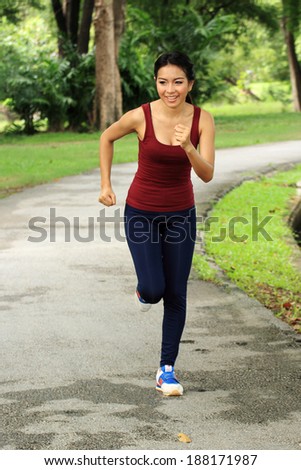 Asian woman running in park in sunshine on the holiday