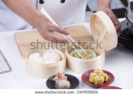 Chef using chopsticks hold Chinese dumpling / Cooking Dim sum concept