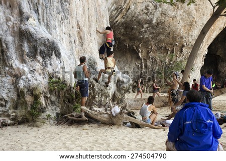 KRABI, THAILAND - MARCH 28, 2015: Rock climbers climbing the wall on Phra Nang beach, One of the most popular rock climbing locations in Krabi, Thailand