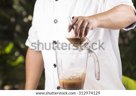 Chef putting coffee to blender with ice