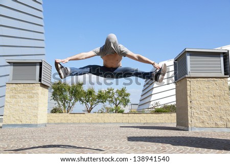 boy jumps with his head covered while doing the splits