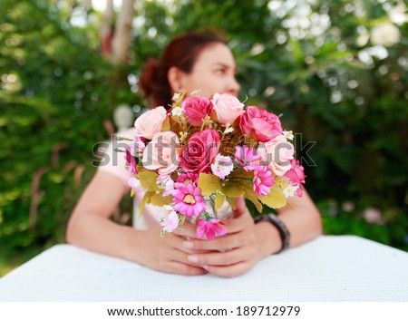Closeup photograph of a woman showing a bunch of assorted flowers