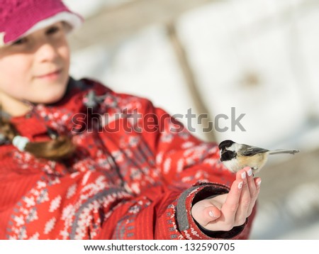 Girl hand-feeding a black-caped chickadee