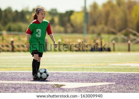 Girl at a soccer practice running with the ball