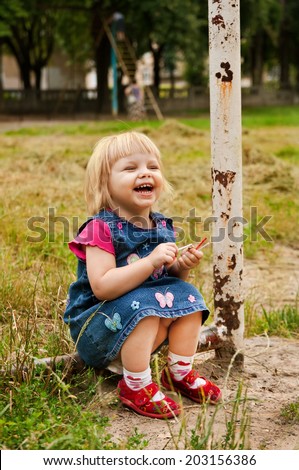 little blonde girl sitting on football field and laughing