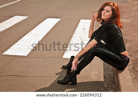 traveler girl in black is sitting near the road and waiting for someone