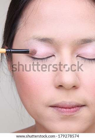 Beautiful asian woman doing make-up on face with cosmetic brush.