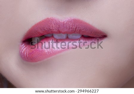 Closeup of sensuous woman biting red lips