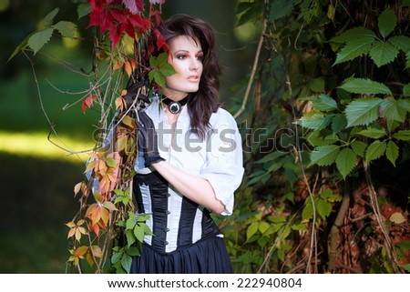 Mysterious woman in Victorian dress among the autumn leaves
