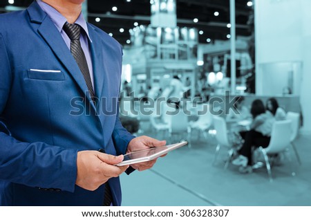 business man holding tablet with blurry event background