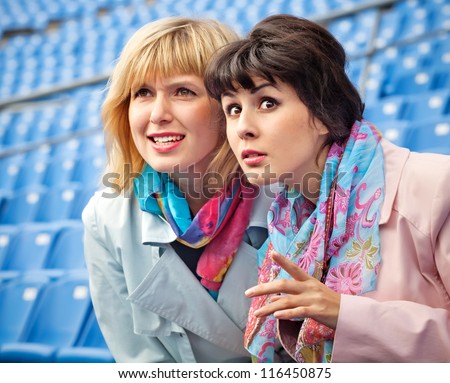 two excited  women fans watching  competition or concert in stadium