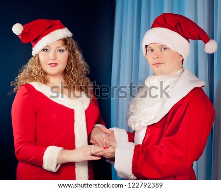 Happy mature couple in love wearing Santa hats near Christmas tree. Fat woman and slim  fit  man.