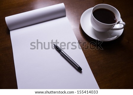 sheet of paper, pen and cup of coffee on desk