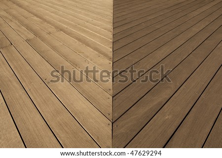 Joint area of wooden deck flooring with small grooves in distinctive lighting condition.