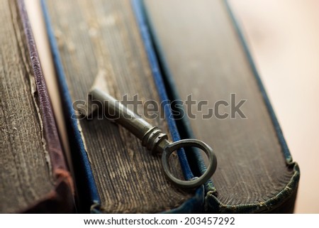 Knowledge, concept image. key to solutions. Old vintage key on old books.