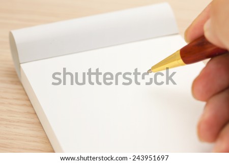 Blank memo pad and a hand holding a pen.