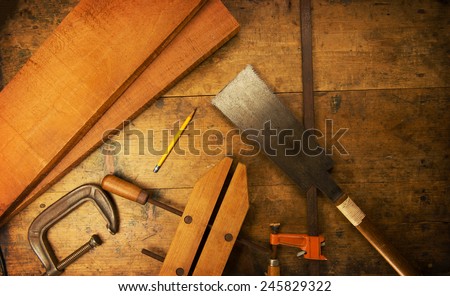 Wood working table. Saw, clamps and wood shavings on a work desk under incandescent light.
