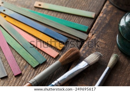 Wood color samples and brushes on an old wooden surface. Focus is on brown brush bristle.