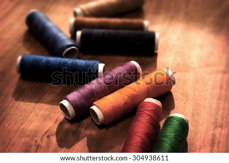Colored sewing threads on a old work table with impressional tone and feel. Shallow depth of field.