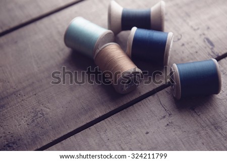 Old sewing thread wooden reels or bobbins on a old rustic work bench. Intentionally shot in muted retro-vintage tone and shallow depth of field. (soft focus)