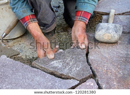 closeup of a senior, paving a patio with natural stones