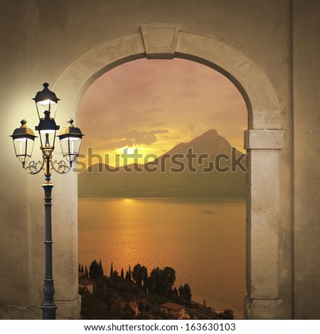 arched door with view to sunset landscape, romantic mood with burning lantern
