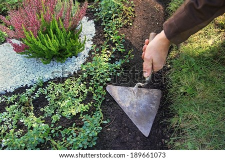 grave cultivation and maintenance, gardener planing with a trowel
