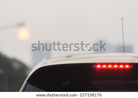 Third brake lights of white car in foggy evening
