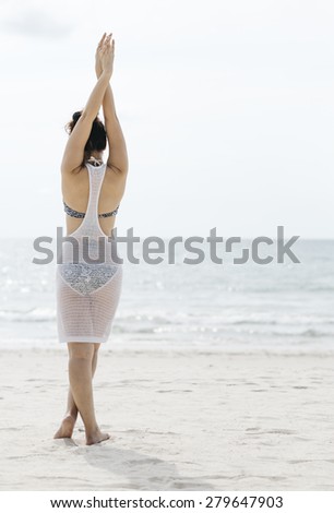 Thai woman stretching and turn back to camera on the sunny beach