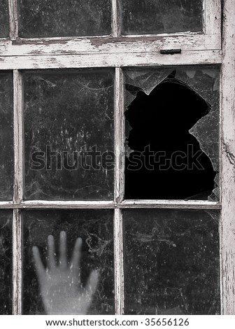 Hand reaches up to touch old dirty Window with focus on smashed pane