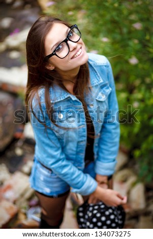 happy young female outdoors in jeans wear smiling wearing glasses and hat view from above