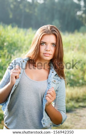 waist up portrait of beautiful teenage girl in jeans wear looking at camera