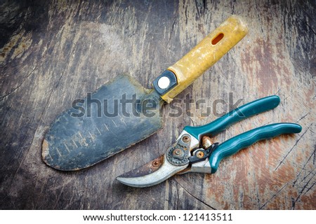 spade tool and cutting tool on a grungy Wooden Table