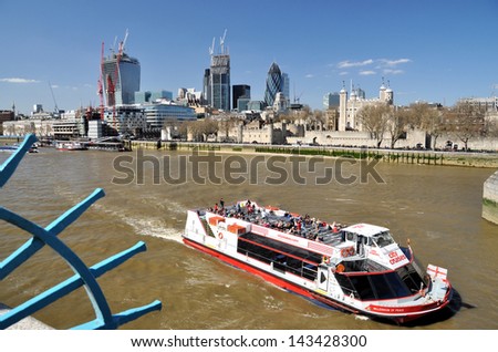 LONDON - MAY 1. River pleasure boat sailing down river on the Thames with the tower of London and new buildings under construction beyond on May 1, 2013, in London, UK.