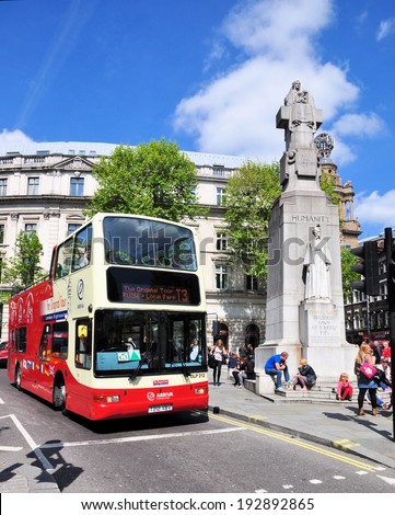 LONDON - MAY 3. An open top double deck sightseeing bus on May 3, 2014, passing the Edith Cavell memorial in St Martin\'s Place, London, a nurse captured and executed by the Germans in 1915.