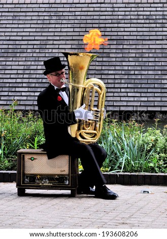 LONDON - MAY 3. Street entertainer on the South Bank of the River Thames apparently playing a tuba while creating fire from his instrument on May 3, 2014 in London, UK.