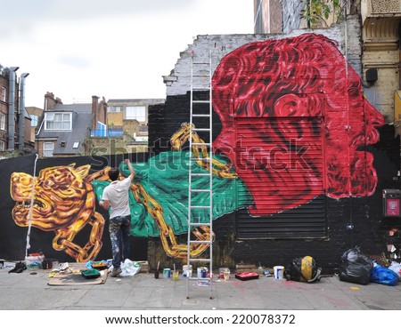 LONDON - SEPTEMBER 27. Street artist at work on derelict site hoarding on September 27, 2014 in Hanbury Street in the east end of London, UK.