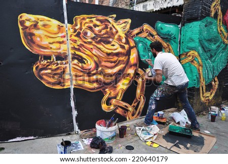LONDON - SEPTEMBER 27. Street artist at work on derelict site hoarding on September 27, 2014 in Hanbury Street in the east end of London, UK.