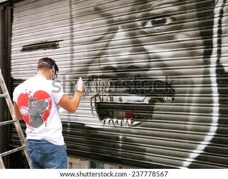 LONDON - SEPTEMBER 27. Street artist at work on shop shutter on September 27, 2014 in Hanbury Street at Shorditch in the Borough of Tower Hamlets, east London, UK.