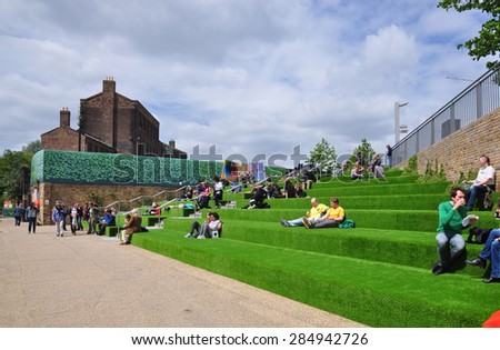 LONDON - MAY 25, 2015. Visitors relax on the terrace at Granary Square, King's Cross, an area undergoing major regeneration in the Borough of Camden, London, UK.