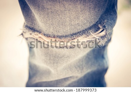 Closeup of tear in old worn out jeans in vintage tone