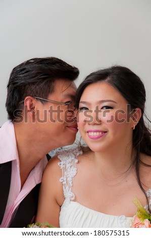 Bride kisses groom smiling to camera after wedding ceremony